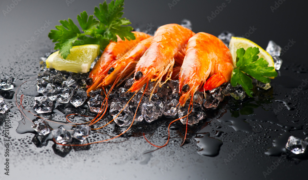 Shrimps. Fresh prawns on a black background. Seafood on crashed ice with herbs. Healthy food, cookin