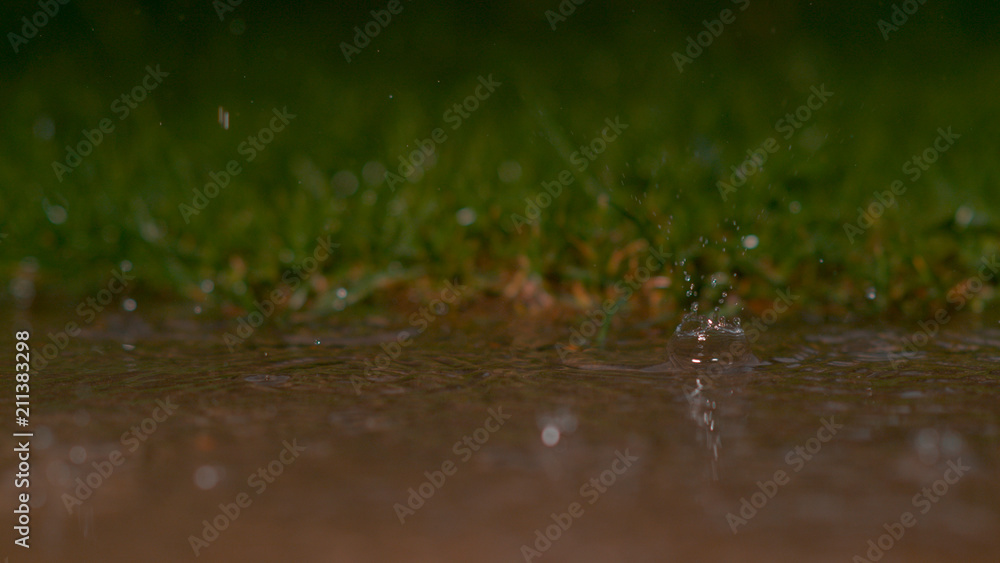 自由度：暴雨期间玻璃状雨滴落入浑浊池塘的美丽镜头