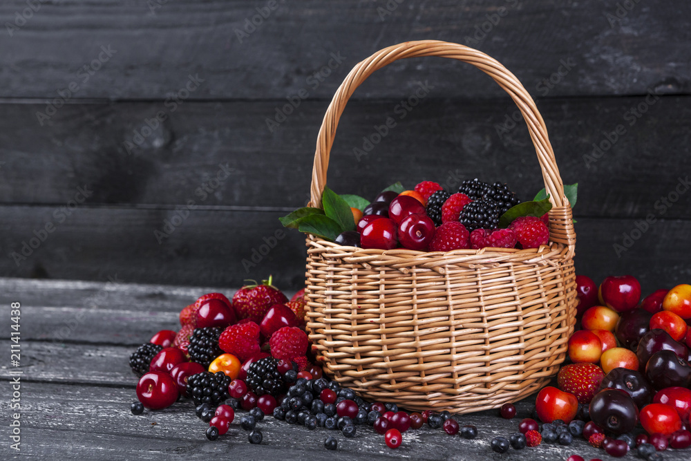 Fresh forest berries in basket on wooden table. Copy space