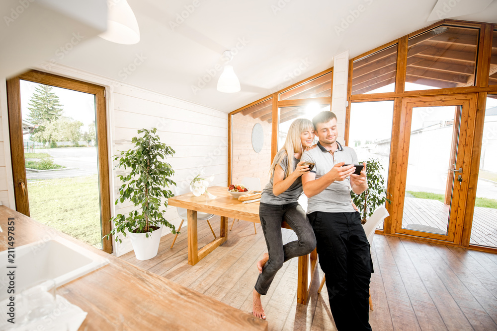 Portrait of a young and happy couple standing together in the cozy interior of the modern wooden hou