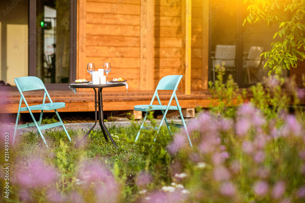 Wooden country house backyard with table and chairs outdoors during the sunset