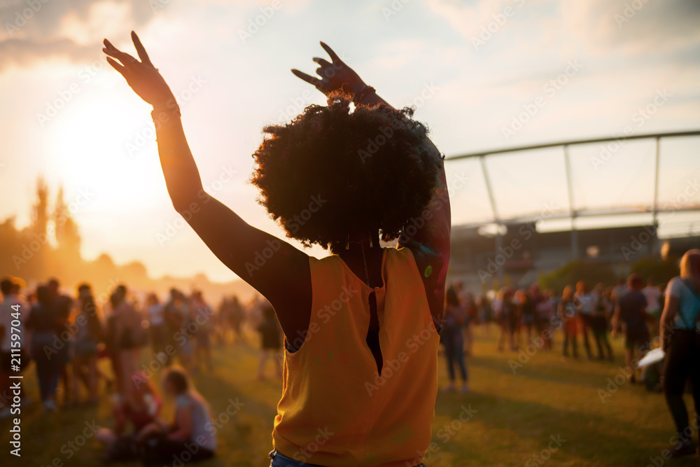 Young African American woman dancing at summer holi festival, back view