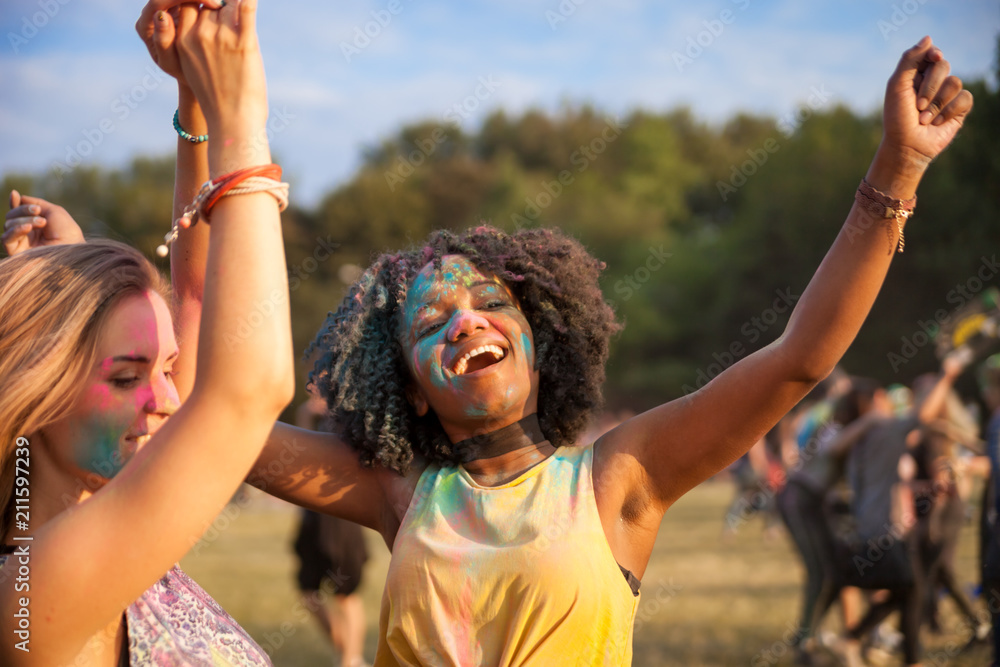 两个多民族女孩穿着五颜六色的粉末跳舞，庆祝暑假