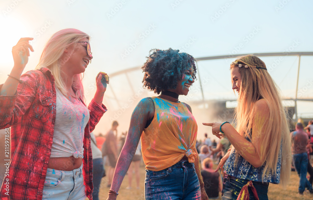 Multiethnic group of friends with colorful powder on clothes and bodies at summer holi festival havi