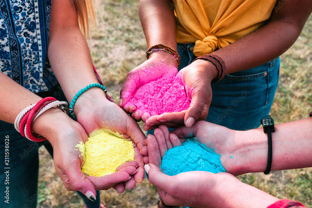 Multiethnic group of friends holding colorful powder in hands at holi festival