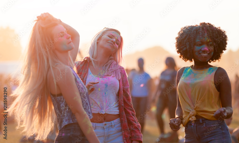 Multiethnic girls covered in colorful powder dancing and celebrating summer holi festival