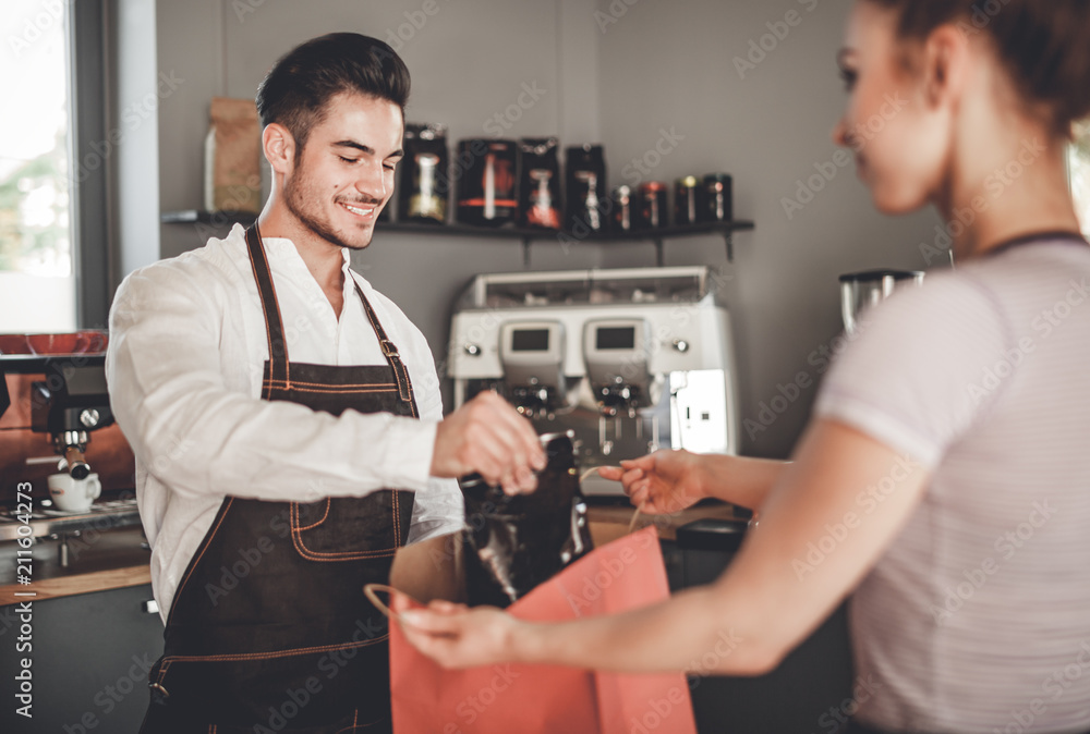 Professional barista giving shopping bag to customer at coffee shop, cafe small business