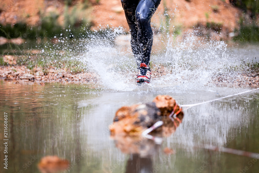 Dynamic run through river splashing water, cross country trail