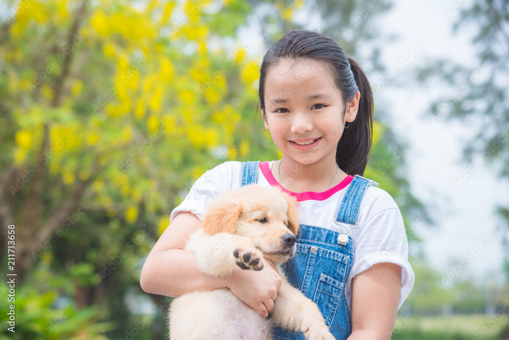 年轻的亚洲女孩在公园里抱着一只小金毛猎犬