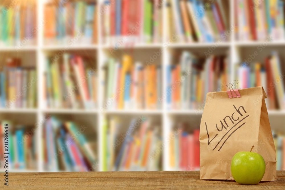 Composite image of lunch bag with apple on wooden table 