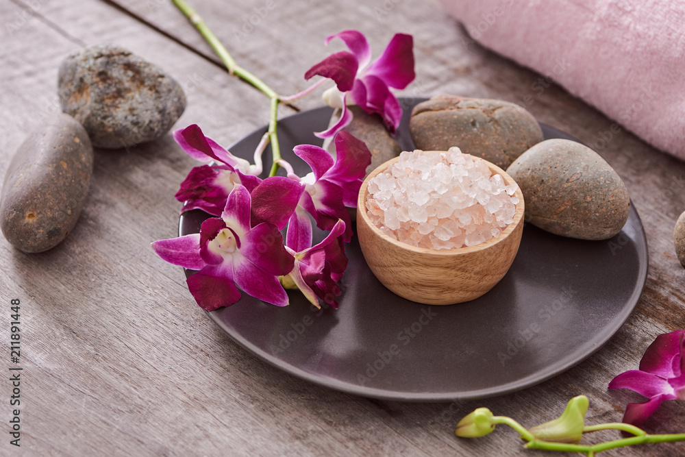 bath salt at bamboo bowl and orchids flowers on dark wood