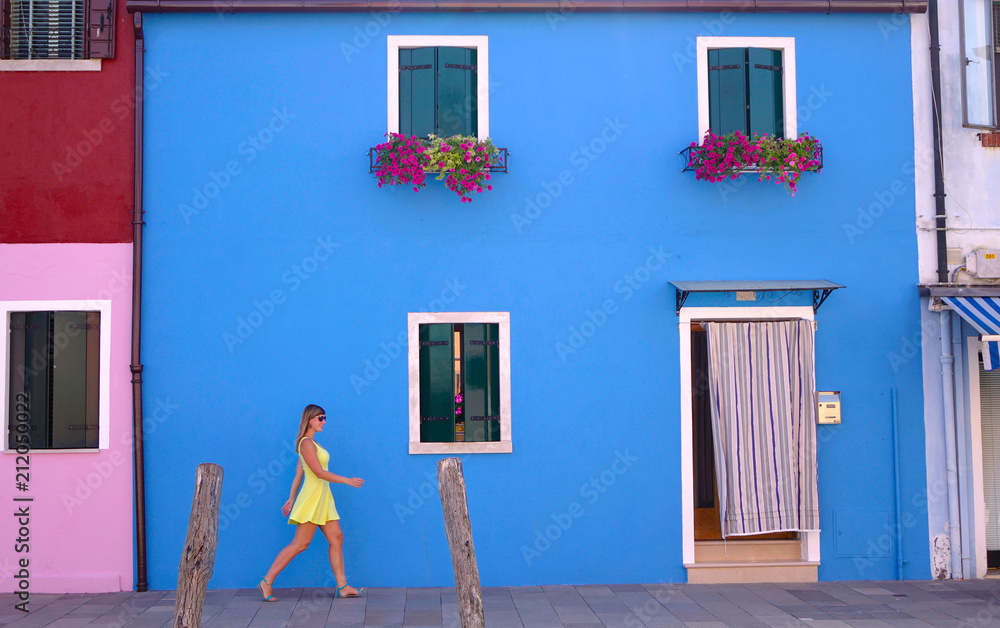 Young woman walks around and explores the colorful streets of Burano, Italy.