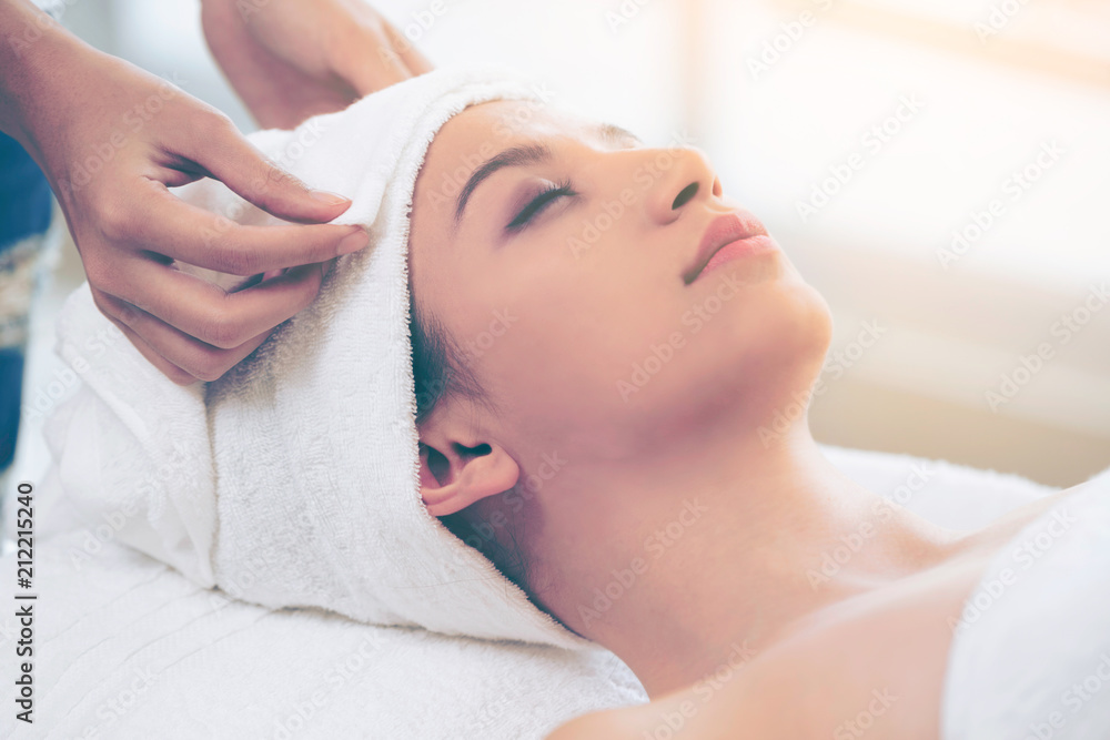 Relaxed young woman lying on spa bed for massage.