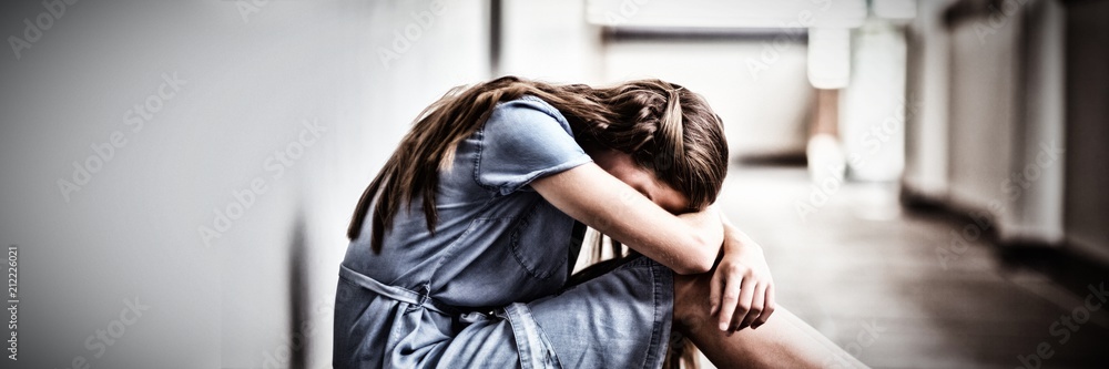 Sad schoolgirl sitting in corridor