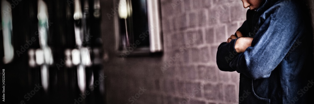 Boy standing alone by wall in corridor