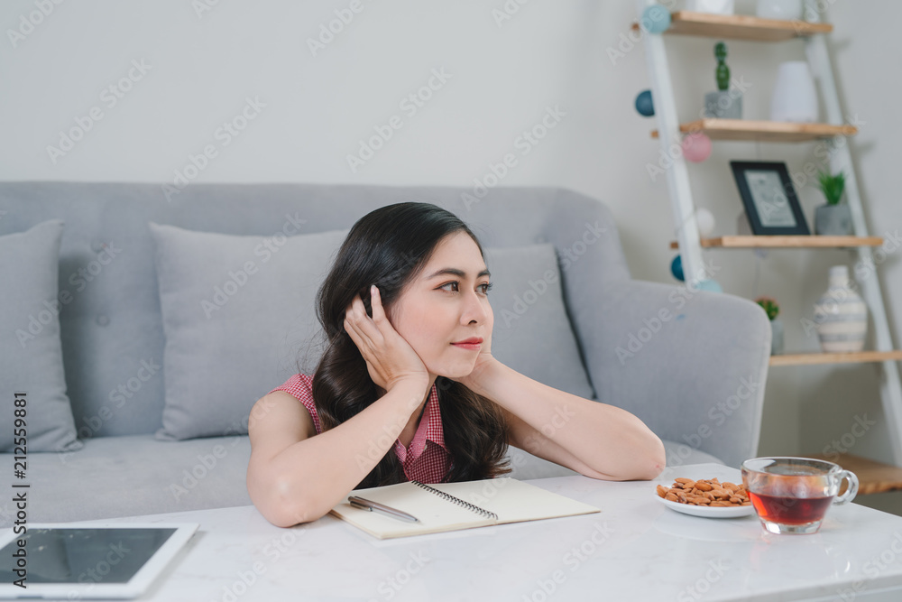 young asian woman thinking ideas while sitting at a stone desk in her apartment