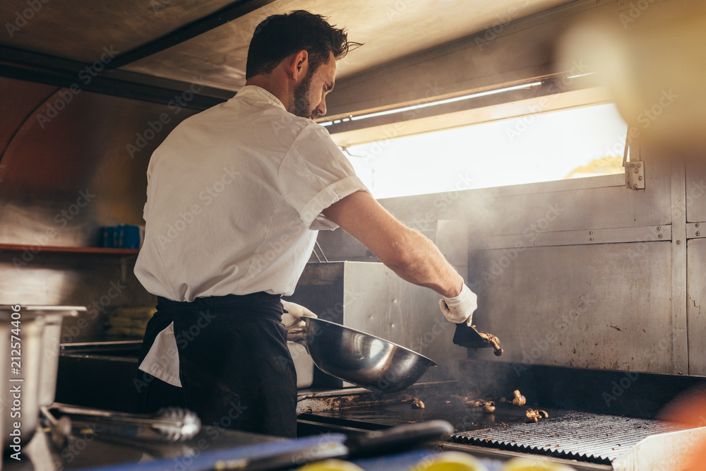 Male cook preparing a dish in food truck