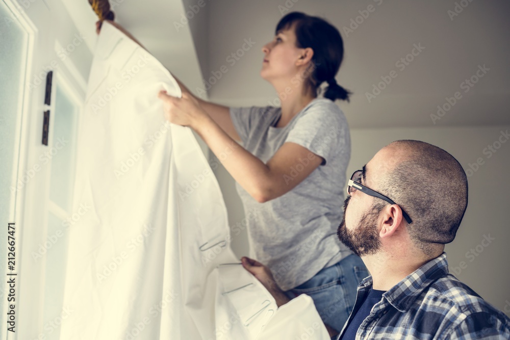 People installing window curtain