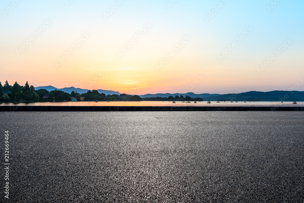 Empty asphalt road and hills silhouette at sunset