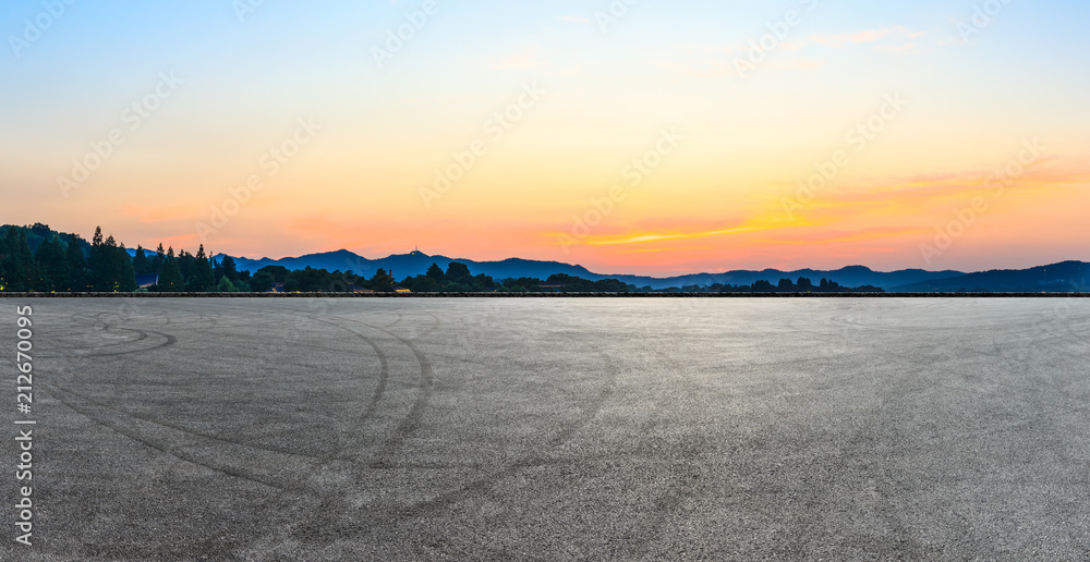 Asphalt road and hills silhouette at sunset