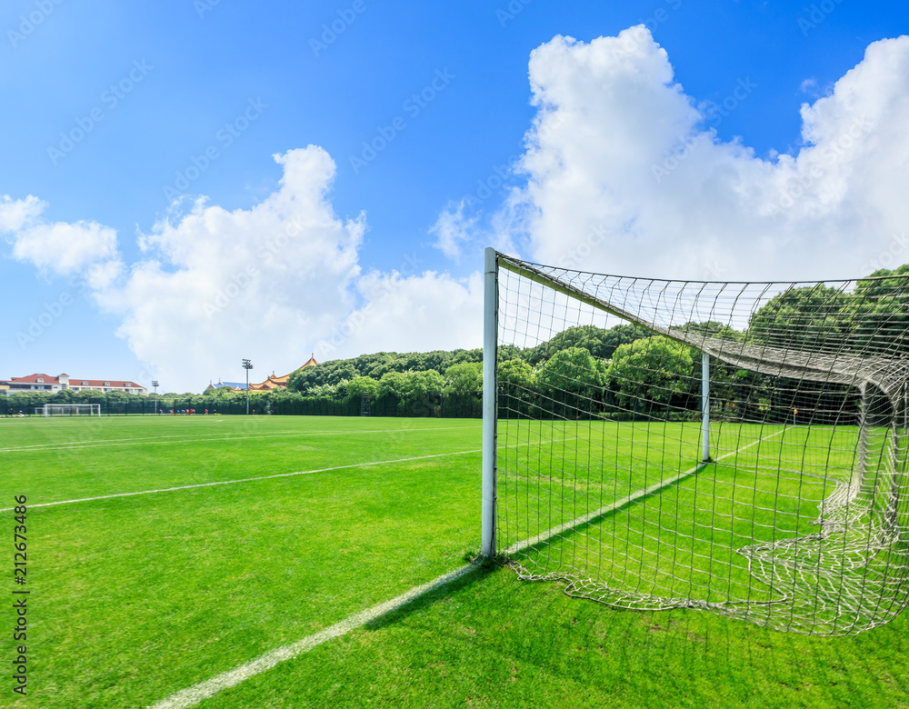 Green football field under blue sky background