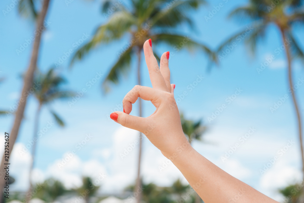 假期，海滩休息。在夏季海滩的背景下，女人的手展示出OK的手势