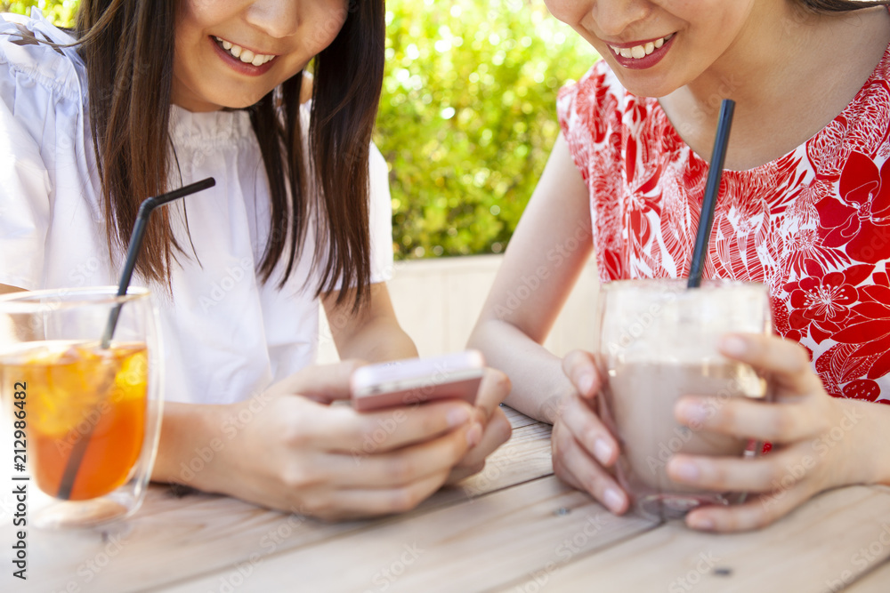 ドリンクを飲みながら、スマートフォンを操作している女性たち。