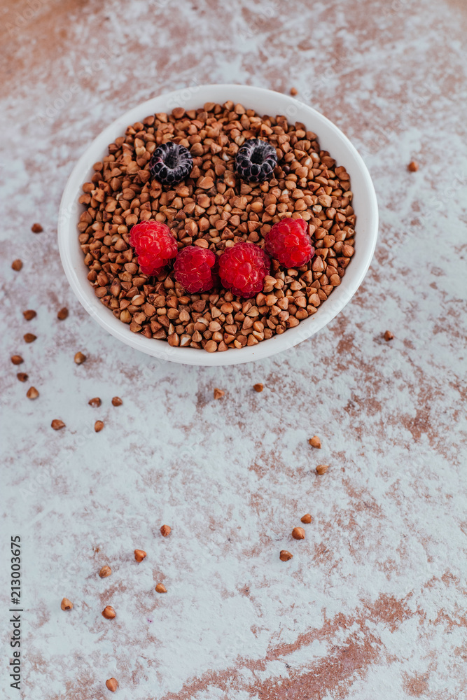 Smile from blackberries and raspberries in a plate with buckwheat and rolls.