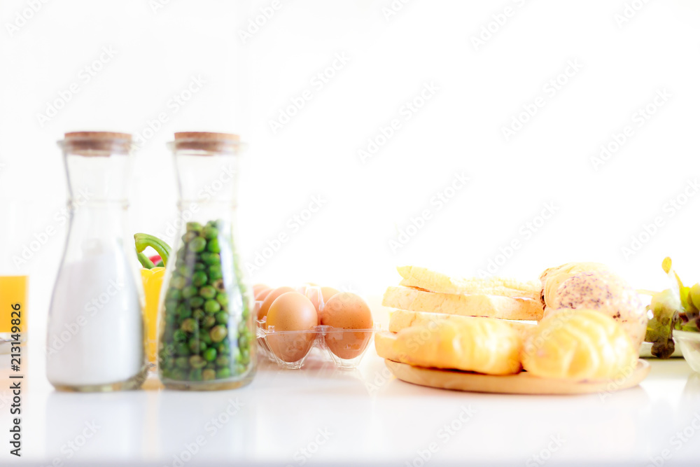 The eggs put in the plastic tray and bread on the white table and other stuff that gives a lot of en