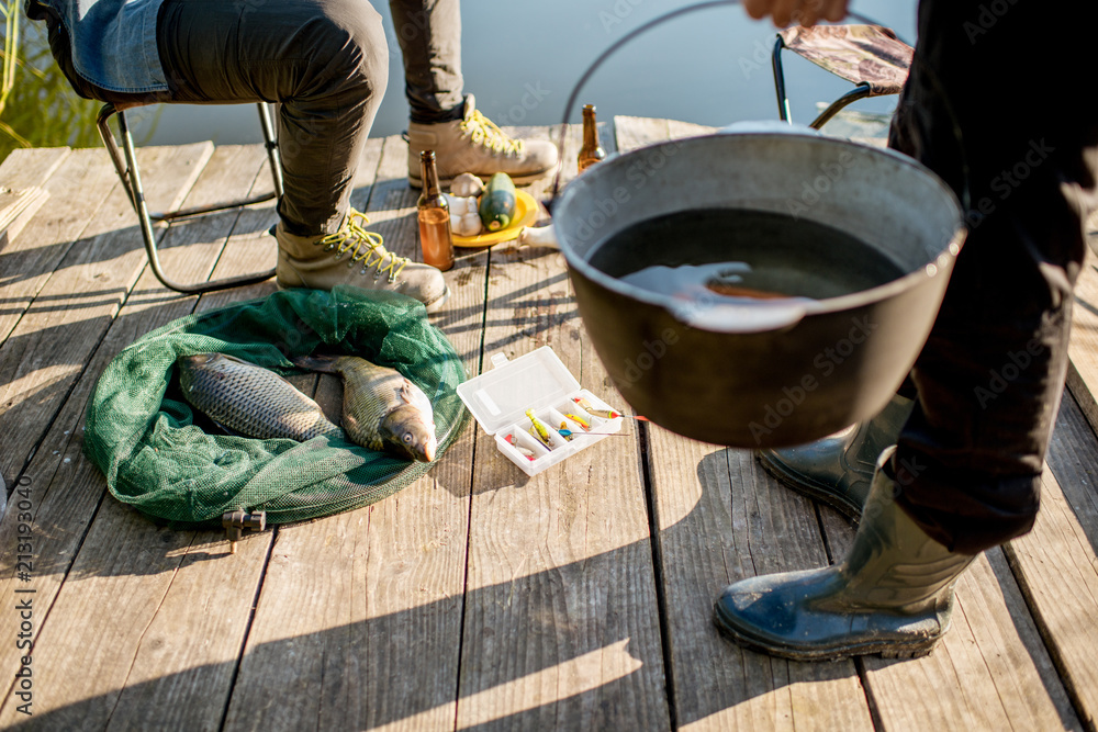 两名渔民早上在湖边的木码头野餐时准备了一些食物