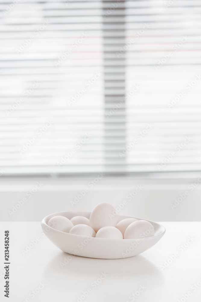 Raw white eggs on plate on table.