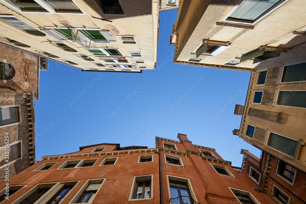 Venice buildings and houses facades low angle view in a sunny day, blue sky in Italy