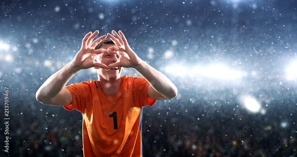 Soccer player celebrates a victory on the professional stadium while it’s snowing.