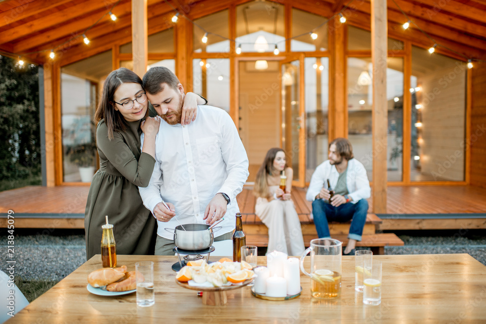 Two lovely couples enjoying evening time on the backyard of the modern wooden house outdoors