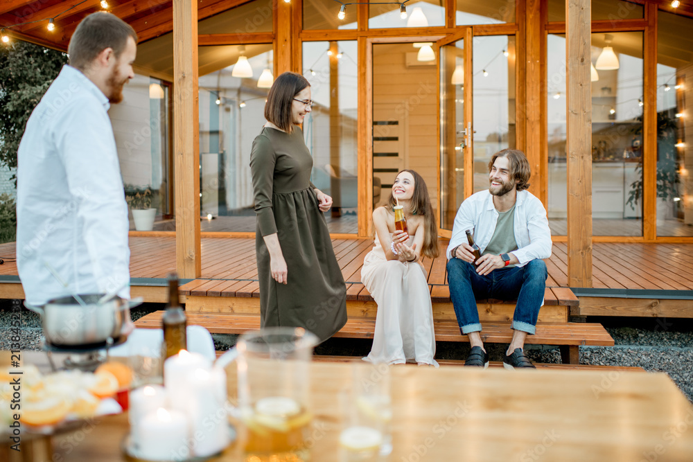 Friends enjoying evening time on the backyard of the wooden house outdoors