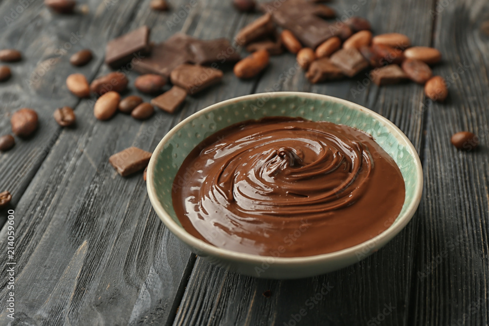 Bowl with molten chocolate on wooden table