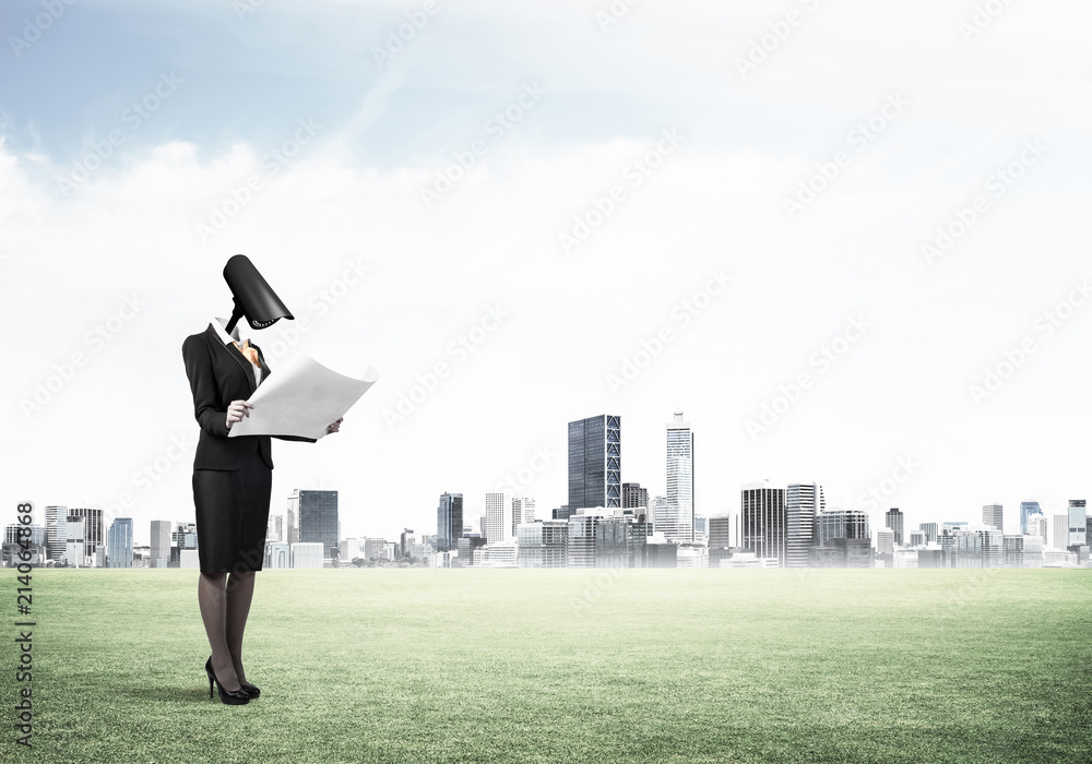 Camera headed woman standing on green grass against modern citys