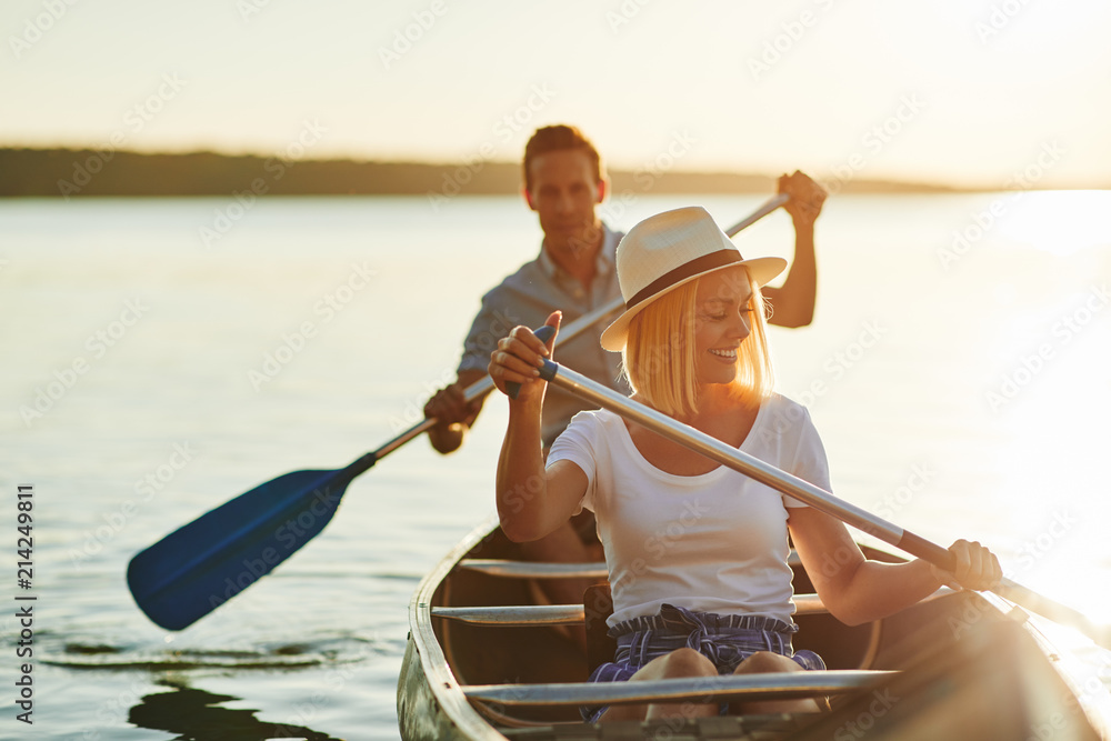 Smiling couple paddling their canoe on a lake in summer