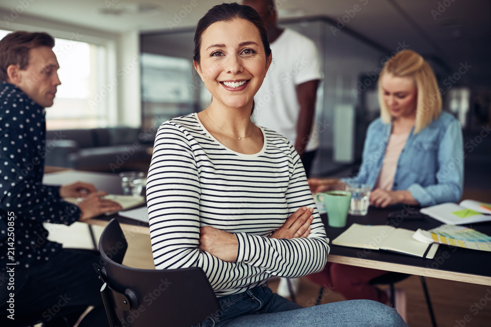 Smiling young businesswoman sitting with colleagues in an office