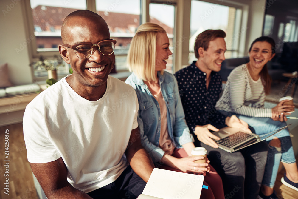 Smiling African businessman sitting with coworkers in a modern o