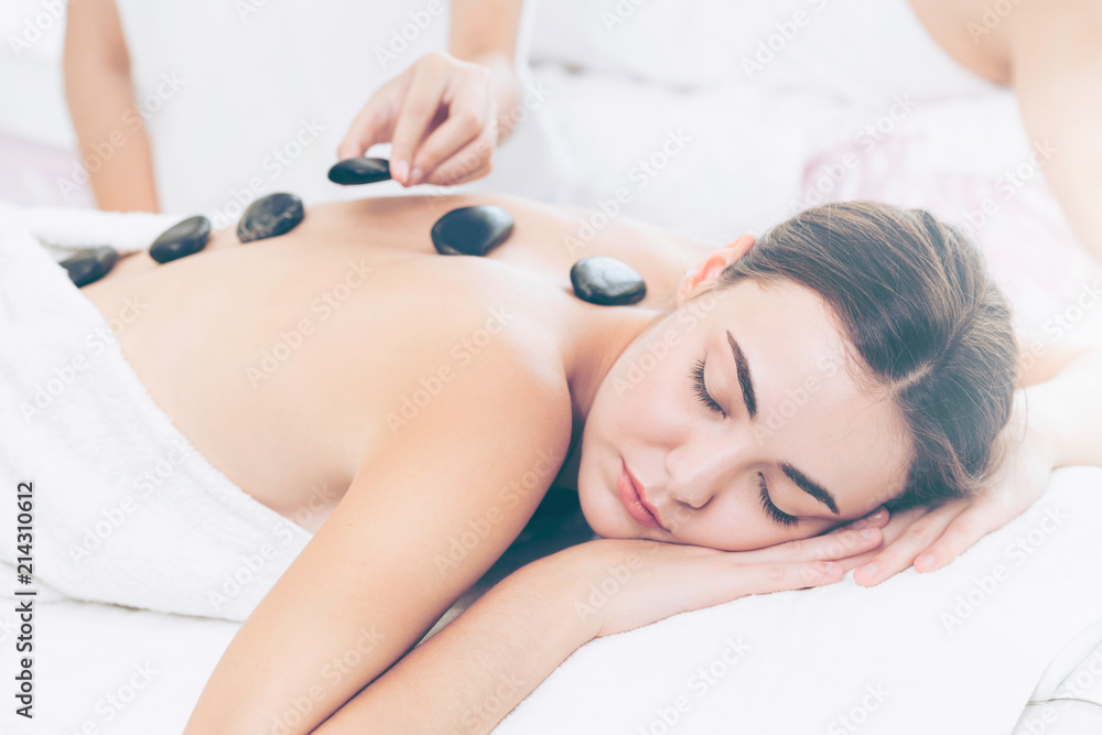 Hot stone massage treatment by therapist in spa.