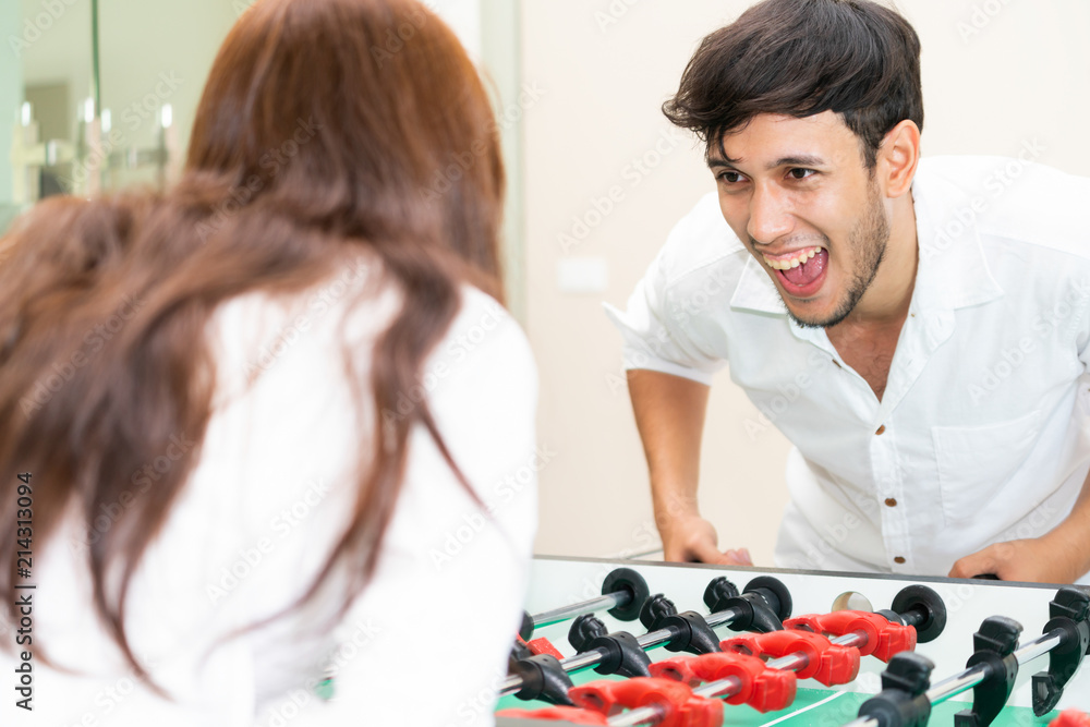 Happy couple playing foosball table.