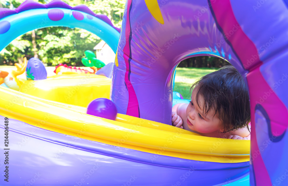 Happy toddler boy playing in his backyard pool