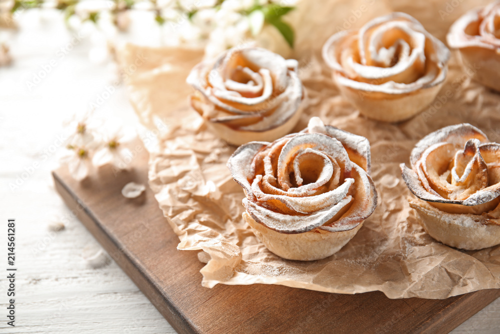 Tasty apple roses from puff pastry on wooden board