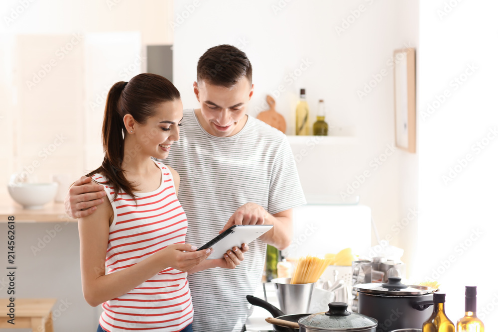 年轻夫妇在厨房里用平板电脑阅读电脑食谱