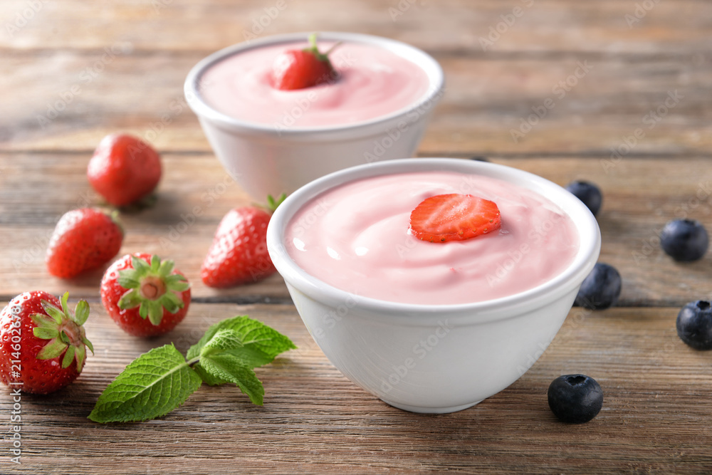 Bowl with yogurt and berries on wooden table