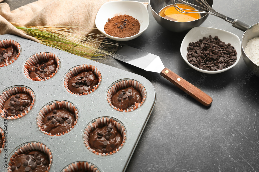 Baking tin with tasty chocolate muffins on table