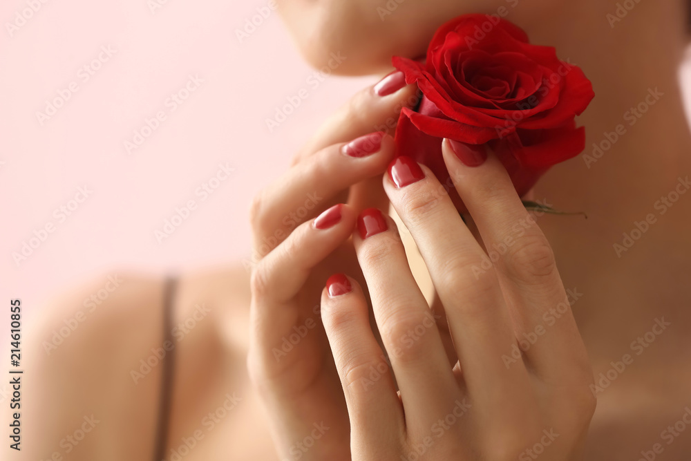 Young woman with beautiful manicure and flower on color background, closeup