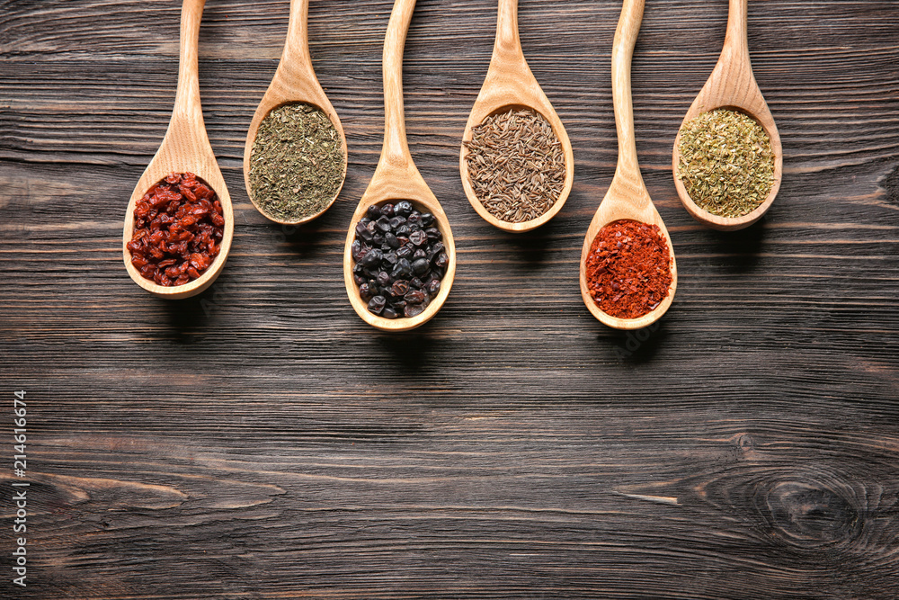 Spoons with different dry spices on wooden  background