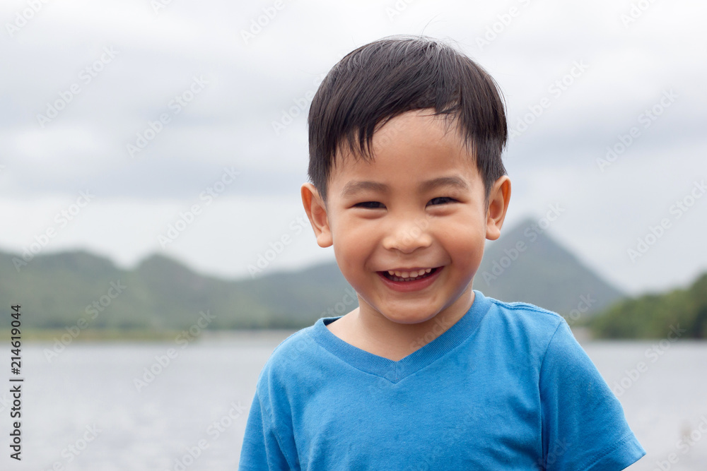 快乐的笑脸亚洲男孩，户外山地背景，复制太空图像。